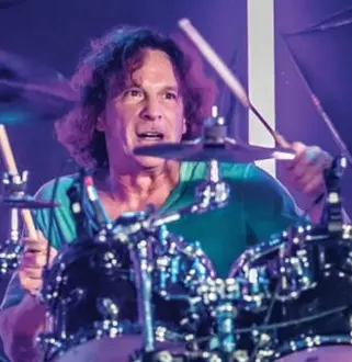 A man playing drums in front of purple lights.