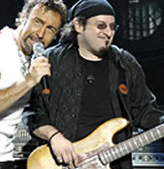 A man holding a microphone and another man playing guitar.