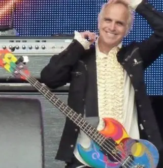 A man holding a guitar in front of a stage.