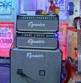 A stack of three amps in front of a guitar.