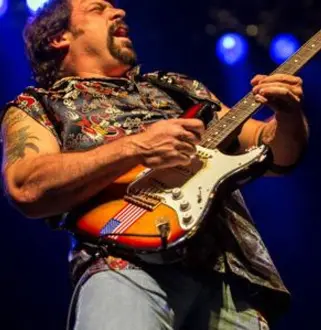 A man with tattoos playing an electric guitar.