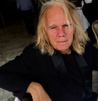 A man with long blonde hair sitting in a chair.