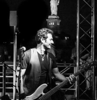 A man playing guitar on stage in front of an audience.