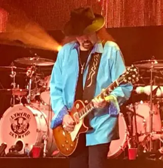 A man in blue jacket playing guitar on stage.