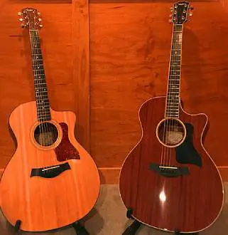 Two guitars are sitting on a table in front of a wall.