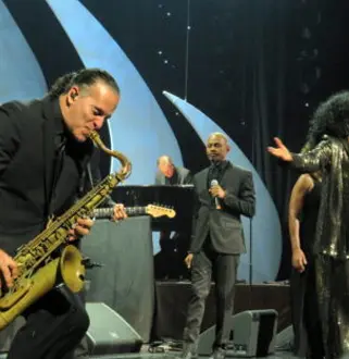 A man playing the saxophone on stage with other people.