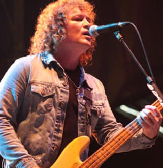 A man with curly hair is playing guitar