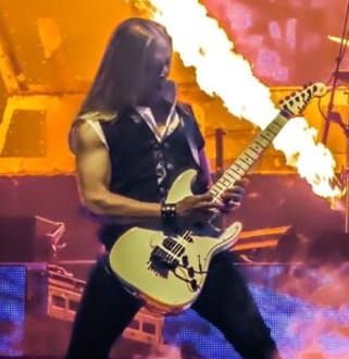 A man with long hair playing an electric guitar.