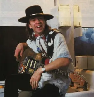 A man in a cowboy hat holding an electric guitar.