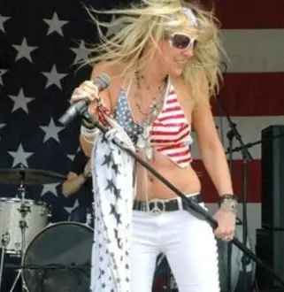 A woman in white pants and red top holding a microphone.