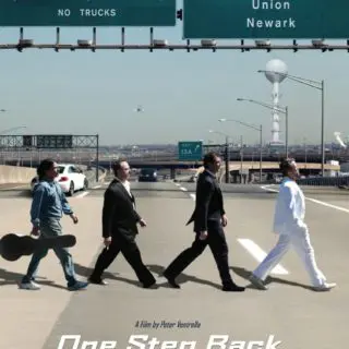 A group of people crossing the street in front of an interstate.